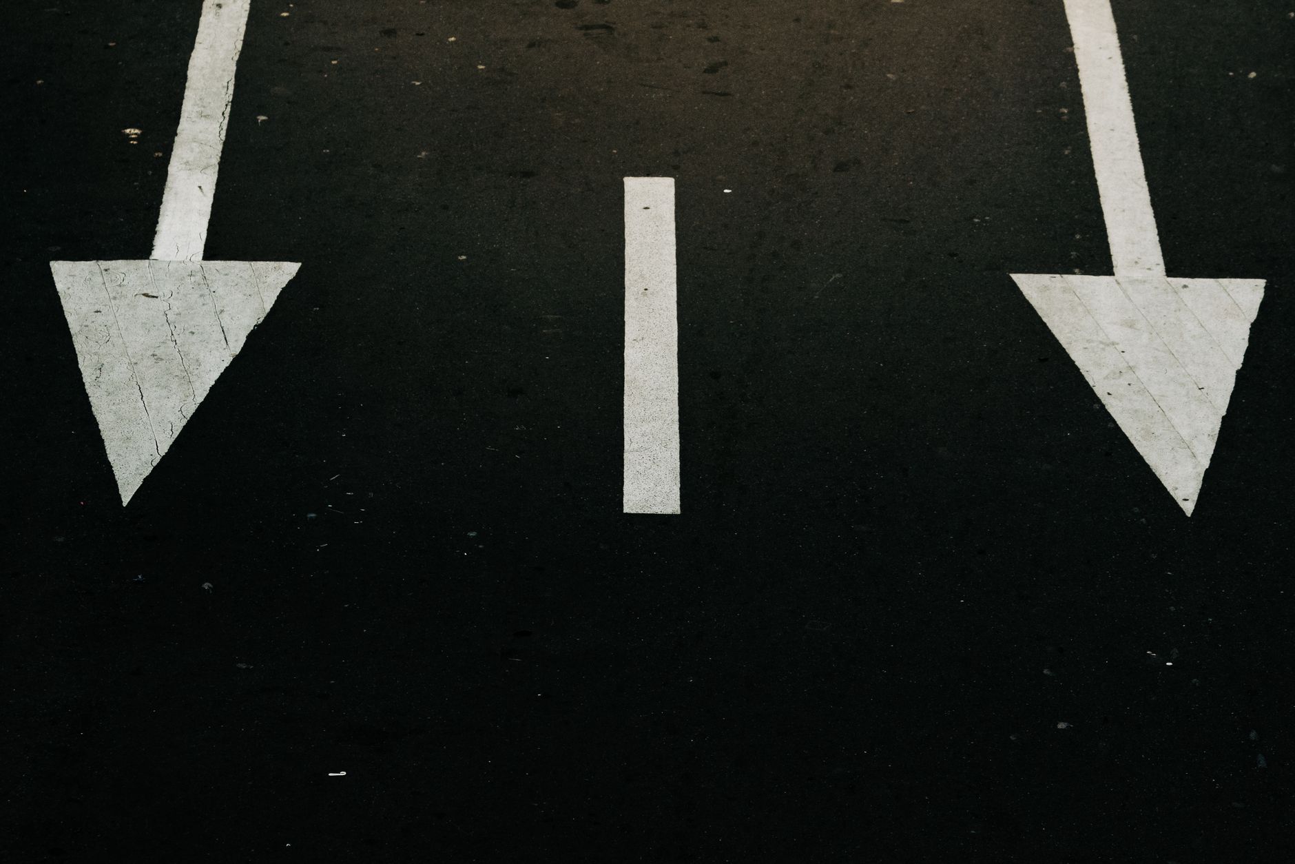Traffic direction arrows on a city street, symbolizing decision and navigation.