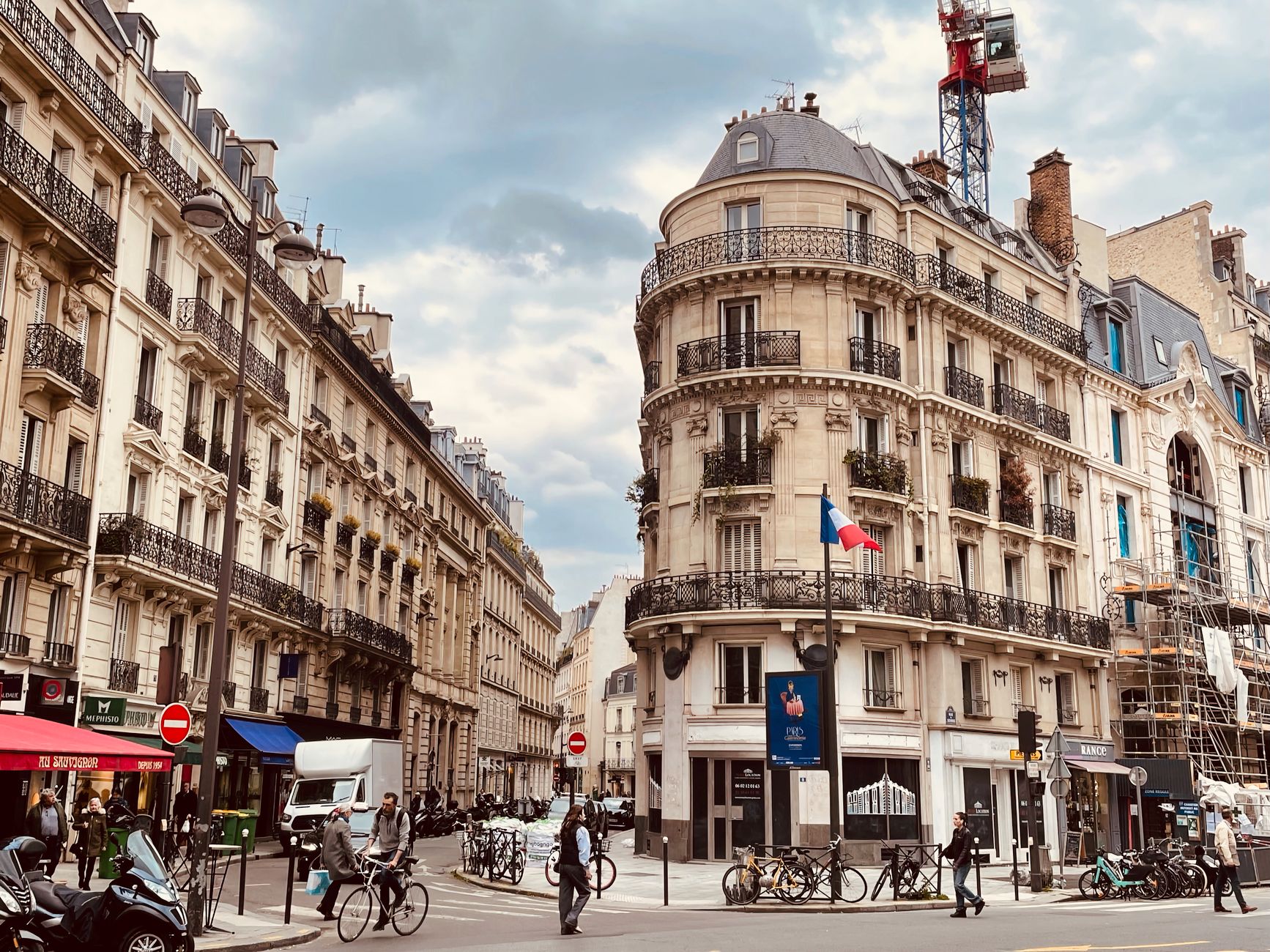 A bustling Paris street scene showcasing iconic Haussmann architecture with people and bicycles.