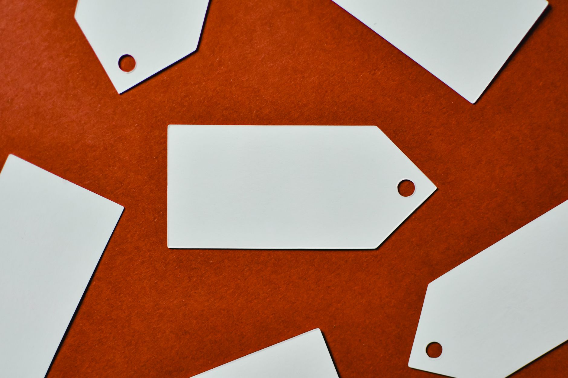 Close-up of white blank tags on a textured red background, perfect for mockup and design use.