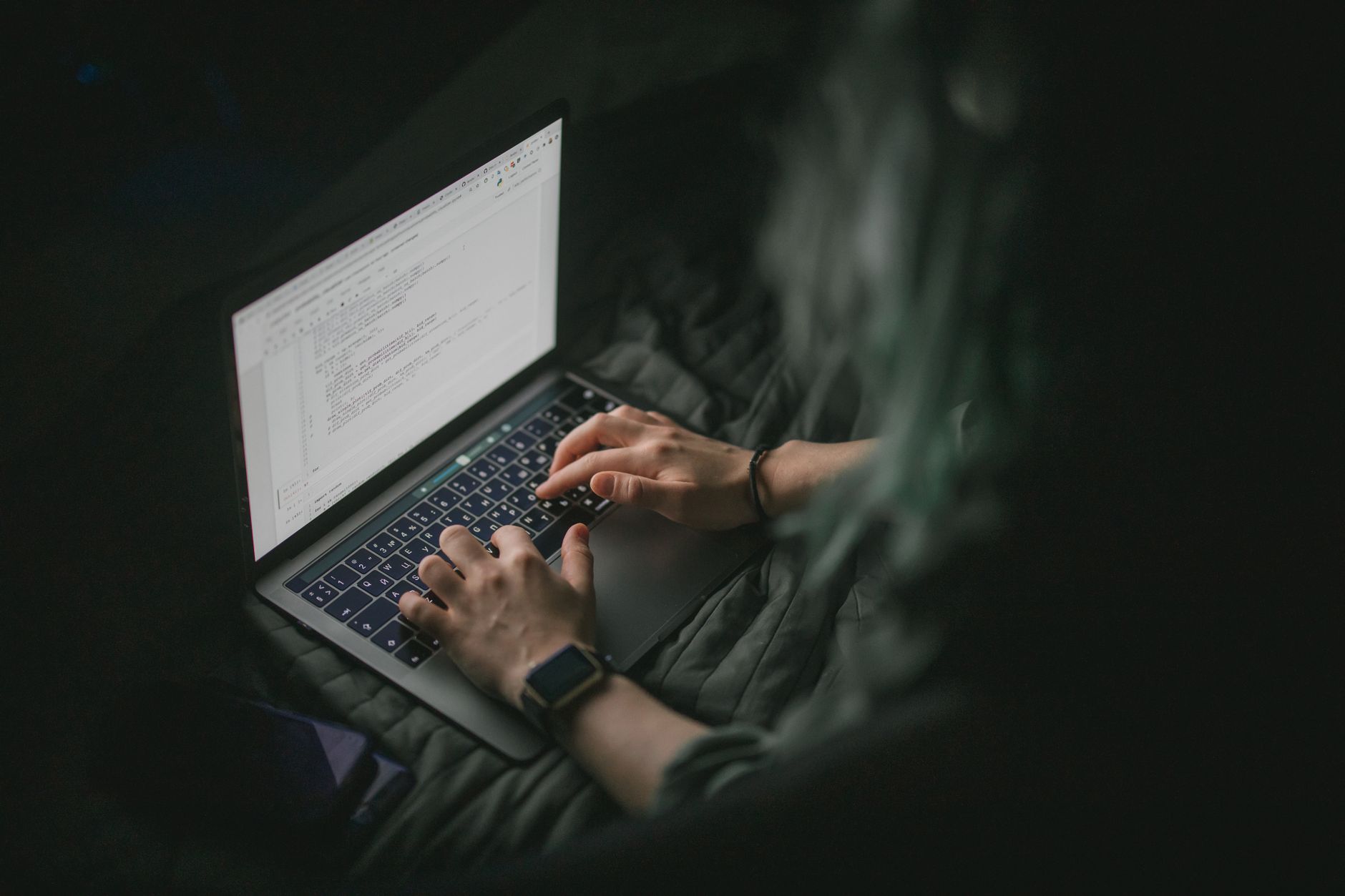Close-up of hands typing on a laptop with code on screen, perfect for work from home and tech themes.